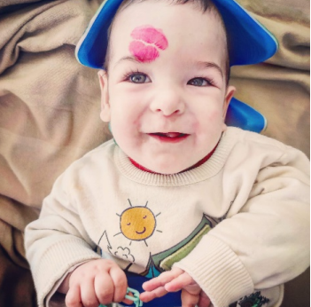 Bebé sonriente con la marca de pintalabios de un beso en la frente