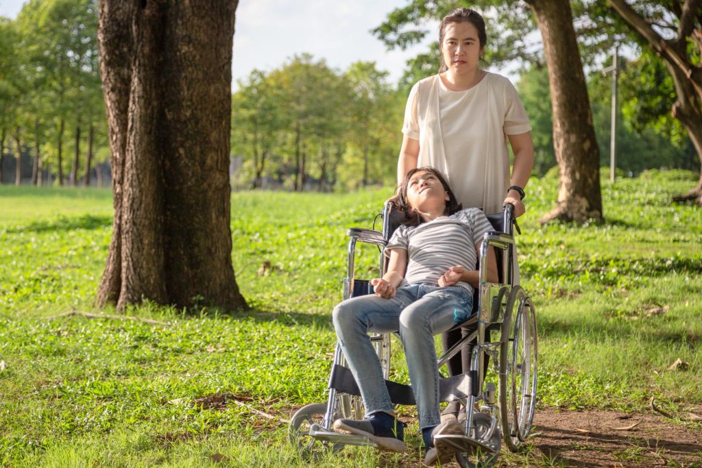 Mujer empuja la silla de ruedas de su hija